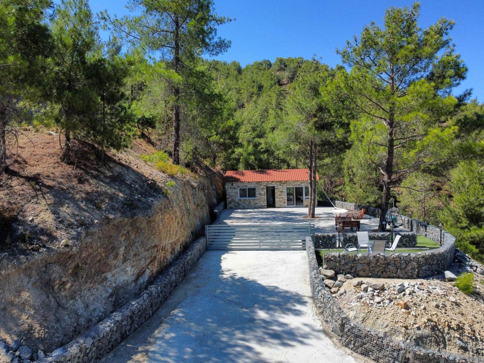 Ο ιδιωτικός δρόμος ανεβαίνει ανάμεσα σε πέτρινους τοίχους προς την κατοικία και τη βεράντα